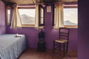 a bedroom with purple walls and a bed and a chair at Il Nibbio - Torretta del Poeta in Morano Calabro