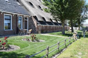 a house with a yard with a fence and flowers at De Hocht in Nes