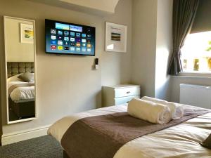 a bedroom with a bed with a flat screen tv on the wall at Stay Lytham Serviced Apartments in Lytham St Annes
