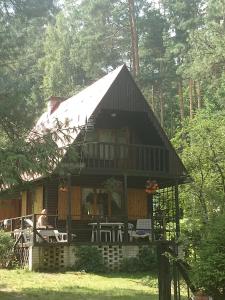 une cabine dans les bois avec une personne assise sur la terrasse couverte dans l'établissement Domek letniskowy Woryty, à Woryty