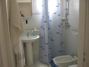 baño con lavabo y cortina de ducha con pájaros. en Casa Giulia Salento, en Porto Cesareo