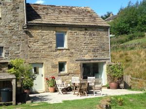 a stone cottage with chairs and a table at The End Place in Pateley Bridge