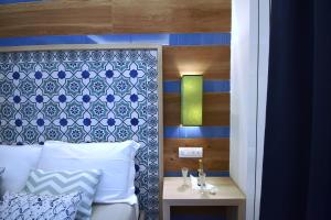 a bedroom with a bed with a blue and white headboard at Melody Sorrento Suites in Sorrento
