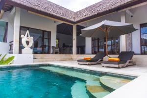 een zwembad met 2 stoelen en een parasol naast een huis bij Villa Michiko in Uluwatu
