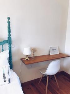 een slaapkamer met een bed, een bureau en een stoel bij Quinta Amarela in Nazaré
