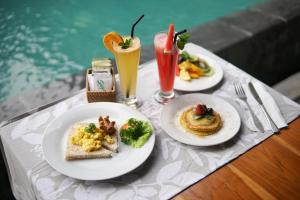 dois pratos de comida numa mesa ao lado de uma piscina em Narda House Ubud em Ubud
