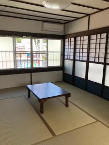 a room with a table in the middle of a room with windows at Amami Weekly House Nico nico in Amami