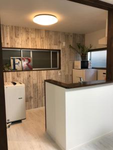 a kitchen with a white counter and wooden walls at Amami Weekly House Nico nico in Amami