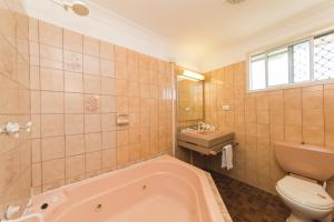a bathroom with a tub and a toilet and a sink at Hampton Villa Motel in Rockhampton +33 photos