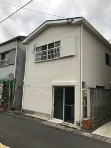 a white house with a window and a balcony at Amami Weekly House Nico nico in Amami