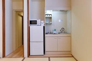 a small kitchen with a refrigerator and a microwave at Hinata-an in Yufu