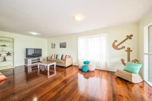a living room with a hard wood floor and a couch at Beachfront at Bribie in Woorim