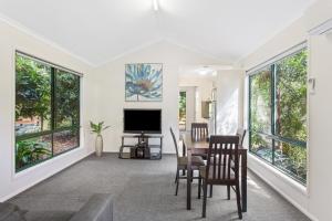 a living room with a table and chairs and windows at Landsborough Holiday Park in Landsborough