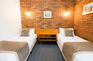 a room with two beds and two tables at Sportslander Motor Inn in Moama