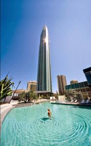 a person in a swimming pool with a tall building at Iconic Q Resort Ocean View in Gold Coast