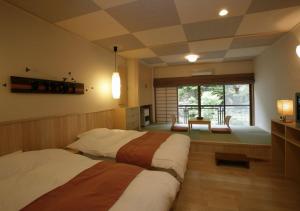 a bedroom with two beds and a table and a window at Hishino Onsen Tokiwakan in Komoro