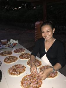 a woman sitting at a table with many pizzas at Beach Hut by S.A.R. in Waingapu