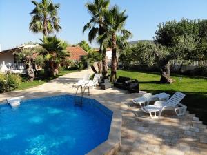 una piscina con sedie bianche e un cortile con palme di Bed and Breakfast La Casetta a Macchia di Monte