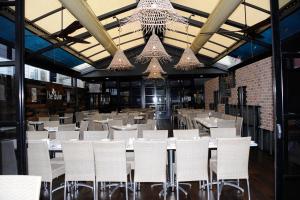 a dining room with white tables and chairs and chandeliers at Duke of Wellington Hotel in New Lambton