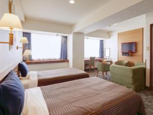 a hotel room with two beds and a television at Hotel Roco Inn Okinawa in Naha