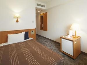 a room with a bed and a table with a lamp at Hotel Roco Inn Okinawa in Naha