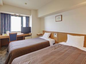 a hotel room with two beds and a desk at Hotel Roco Inn Okinawa in Naha +17 photos