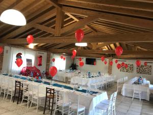 een feestzaal met witte tafels en rode ballonnen bij La Tenuta di Trimalcione in Pofi