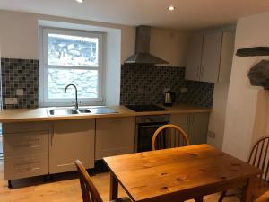 a kitchen with a table and a sink and a window at Plas Eryr apartment in Caernarfon