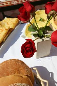 uma mesa coberta com rosas vermelhas e um vaso de flores em Riad CHERRATA em Marrakech