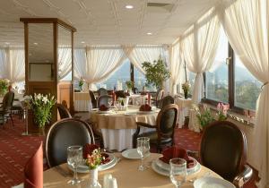 a restaurant with tables and chairs and windows at Park Hotel Moskva in Sofia