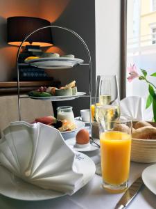 uma mesa com um prato de comida e um copo de sumo de laranja em MOMENTS Boutique Hotel em Bautzen