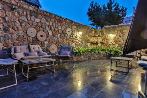 a patio with two chairs and a stone wall at Trys Apartamentai in Palanga