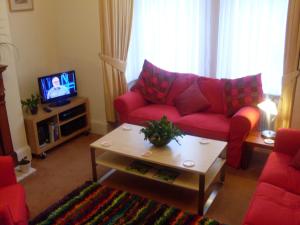a living room with a red couch and a tv at The Swallow Hotel in Bridlington