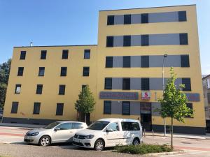 zwei Autos auf einem Parkplatz vor einem Gebäude geparkt in der Unterkunft S Hotel in Maribor