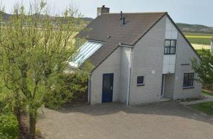 a house with a blue door in a field at villa Ooghduyne in Julianadorp