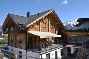 a log house with a deck and mountains in the background at Haus Steinacker in Fiss