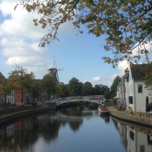 a bridge over a river with a windmill in the background at Appartement Dokkum in Dokkum