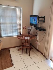 a room with a desk with a television and a chair at B&B on Church in Oudtshoorn