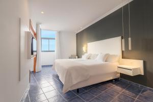 a bedroom with a large white bed and a window at Hotel Mirador Papagayo by LIVVO in Playa Blanca