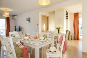 comedor con mesa blanca y sillas en Résidence Odalys Casa d'Orinaju en Oletta