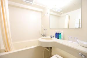 a white bathroom with a sink and a mirror at Hotel Hokke Club Hiroshima in Hiroshima