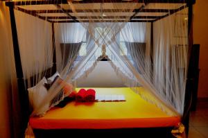 1 cama con cortinas blancas y un arco rojo en Bon Accord Mirissa, en Mirissa