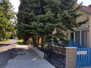 a fence in front of a house with a tree at Jo-Jo's nyaralohaz in Siófok