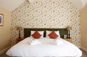 a bedroom with a white bed with towels on it at Bartons Mill Pub and Dining in Basingstoke