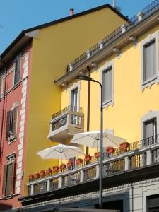 a yellow building with tables and umbrellas on a balcony at Milano Central in Milan