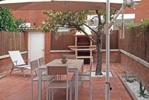 una mesa y sillas bajo una sombrilla en un patio en Vivalidays Casa Pinell - Palafolls - Costa Barcelona en Palafolls