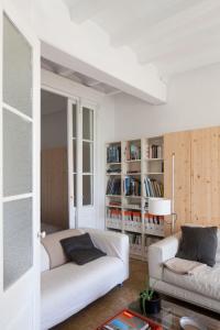 una sala de estar con 2 sofás blancos y un estante para libros. en Apartment E.CO. Home Tarragona, en Tarragona