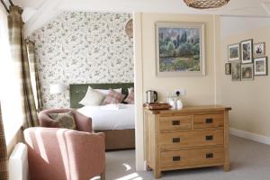 a bedroom with a bed and a chair and a dresser at Bartons Mill Pub and Dining in Basingstoke