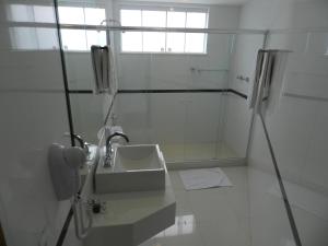 a white bathroom with a sink and a shower at Casablanca Center Hotel in Petrópolis