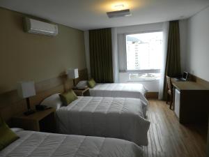 a hotel room with two beds and a window at Casablanca Center Hotel in Petrópolis